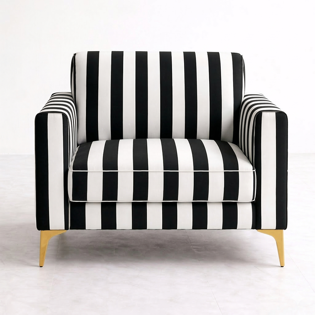Clear front view of a single-seater armchair featuring bold black and white vertical striped fabric upholstery and sleek polished gold metal legs on a light grey tiled floor.